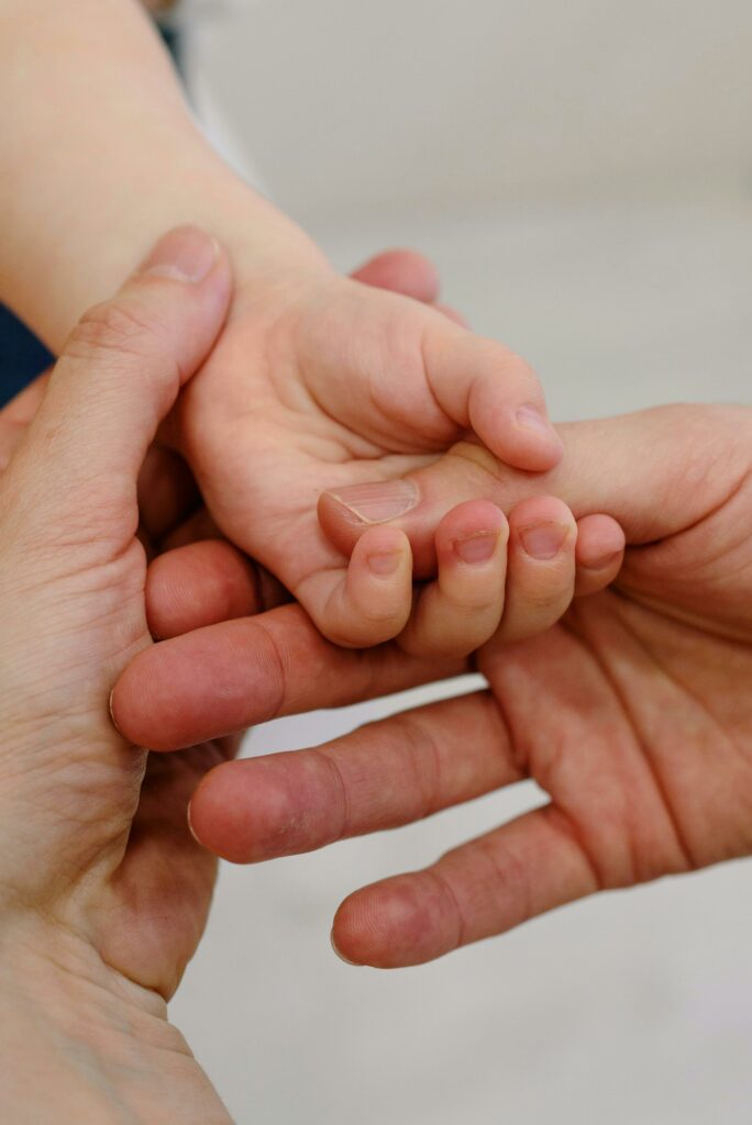 Emotive close-up of adult hands gently holding a baby's hand, symbolizing care and connection.
